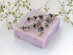 Soap with dry aromatic lavender flowers. Purple handmade soap bar on a white terry cotton towel. Natural toiletries and hygiene