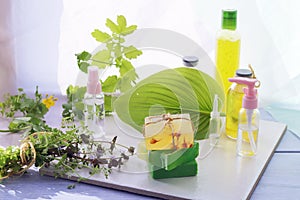 Soap, herbs, spray and bottles with aromatic oil on a wooden windowsill