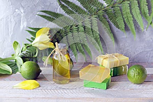 Soap, limes, aromatic oil and fresh flowers on a wooden table