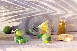 Soap, limes, aromatic oil and fresh flowers on a wooden table