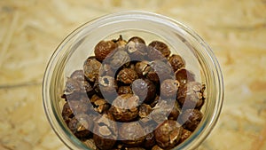 Soap nuts Indian soapberry or washnut glass jar cup, Sapindus mukorossi reetha or ritha from the soap tree shells are photo