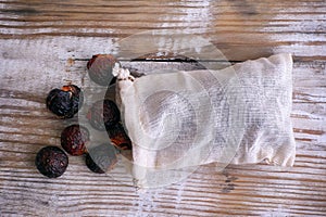 Soap nuts spilling from bag on wooden background. Top view.