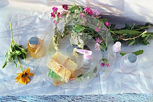 Soap, spray, bouquet of medicinal herbs and glass bottles with aromatic oil on a wooden table