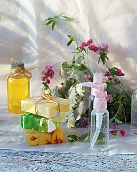 Soap, spray, bouquet of medicinal herbs and glass bottles with aromatic oil on a wooden table