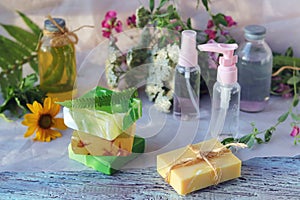 Soap, spray, bouquet of medicinal herbs and glass bottles with aromatic oil on a wooden table