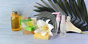 Soap, spray, lily flower, glass bottles with aromatic oil on a wooden table