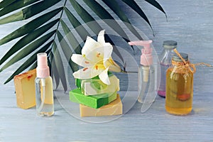 Soap, spray, lily flower, glass bottles with aromatic oil on a wooden table