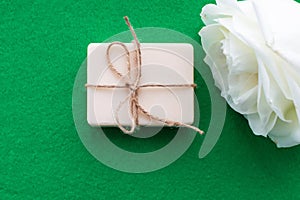 The soap is tied with a rope and a white rose on a green background with a place for the inscription. Concept of hygiene and Spa