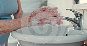 Soap, water and hands of senior person washing at tap for healthy skincare, protection and hygiene at home. Closeup