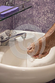 Soaping hands in bathroom sink