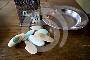 Different soaps and remnants on wooden table with metal grater and dish, preparation for grated soap, lot of solid soap for hygien photo