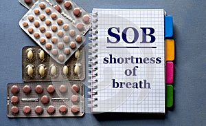 SOB - acronym in a notebook. Nearby are pills on a gray background photo