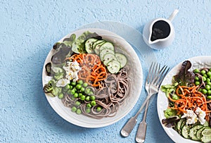 Soba noodles buddha bowl. Buckwheat noodles with vegetables on a blue background, top view. Vegetarian healthy food