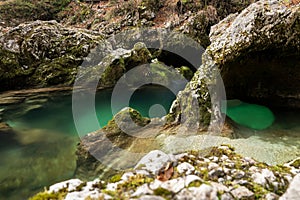 Soca River in Slovenia in a deep gorge surrounded by rocky cliffs covered in lush green moss