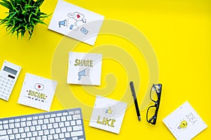Socail media icons on work desk of marketing expert. Digital promotion of goods and services. Yellow background top view photo