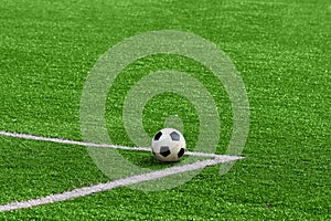 A soccer ball framed by white corner markings on a green football field.