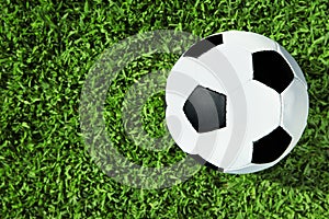 Soccer ball on fresh green football field grass, top view.