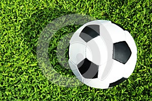 Soccer ball on fresh green football field grass, top view.