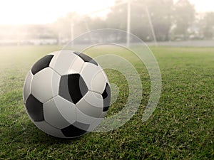 Soccer ball on a grass football field, under the sunset