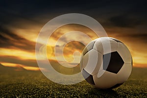 Soccer ball on grass at sunset