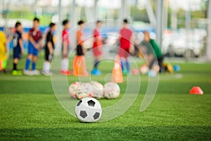 Soccer ball on green artificial turf with blurry soccer team training