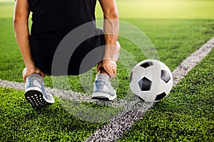 Soccer ball on green artificial turf with footballer is sitting and catch the ankle