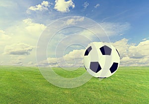 Soccer ball on green field with blue sky