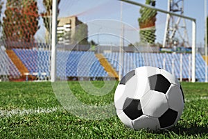 Soccer ball on green football field grass against net