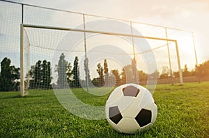 Soccer ball on a green grass field on sunset