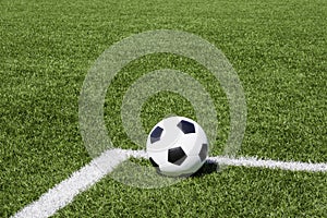 Soccer ball on green synthetic artificial grass soccer sports field with white corner stripe line