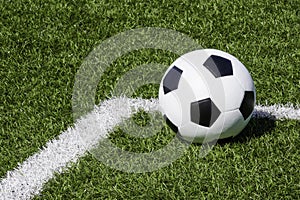 Soccer ball on green synthetic artificial grass soccer sports field with white corner stripe line
