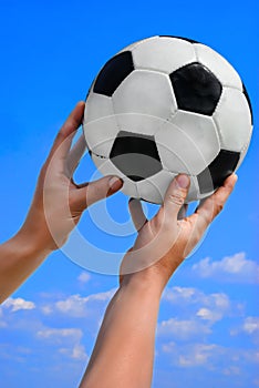 soccer ball in hand on a blue sky