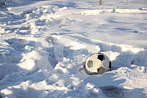A soccer ball is lying on the white snow. Ball on a snow-covered field after the game.