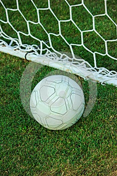 Soccer ball near net on green football  grass.