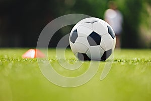 Soccer Ball and Red Cone Marker on Training Pitch. Football Turf. Soccer Stadium in Blurred Background