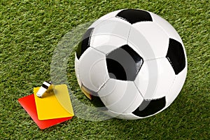 Soccer ball with referee yellow and red cards and chrome whistle on grass background - penalty, foul or sports concept