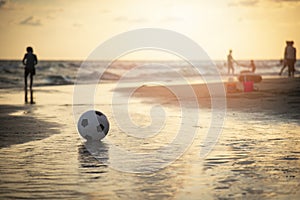 Soccer ball on sand / playing football at the beach sunset sea background