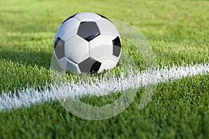 Soccer ball sits on grass field with white stripe