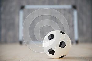 A soccer ball in a small gate on a gray background. Mini football.