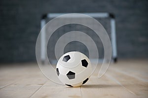 A soccer ball in a small gate on a gray background. Mini football.