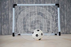 A soccer ball in a small gate on a gray background. Mini football.
