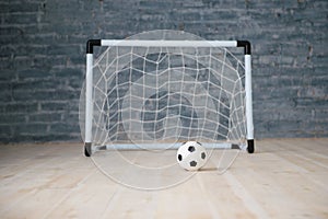 A soccer ball in a small gate on a gray background. Mini football.