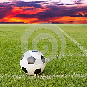 Soccer ball on soccer field against sunset sky