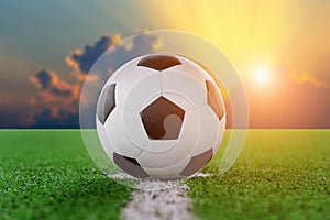 Soccer ball on soccer field at sunset