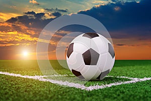 Soccer ball on soccer field at sunset