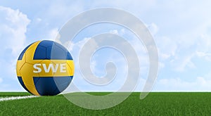 Soccer ball in swedens national colors on a soccer field. Copy space on the right side -