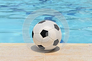 Soccer ball, which serves as a game to entertain when visiting a pool, is located on the edge of the pool.