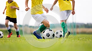 Soccer camp for kids. Boys practice dribbling in a field. Players develop good soccer dribbling skills