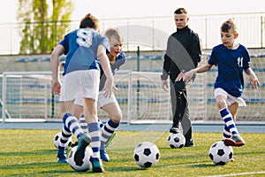 Soccer camp for kids. Boys practice football dribbling in a field. Players develop soccer dribbling skills. Children training