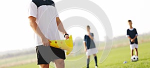 Soccer coach holding yellow training cone during oudoor practice session photo